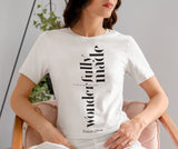 Woman wearing a white t-shirt with text design, sitting on a chair.