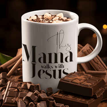 White mug with 'This Mama Walks with Jesus' text, surrounded by chocolate and cinnamon sticks.